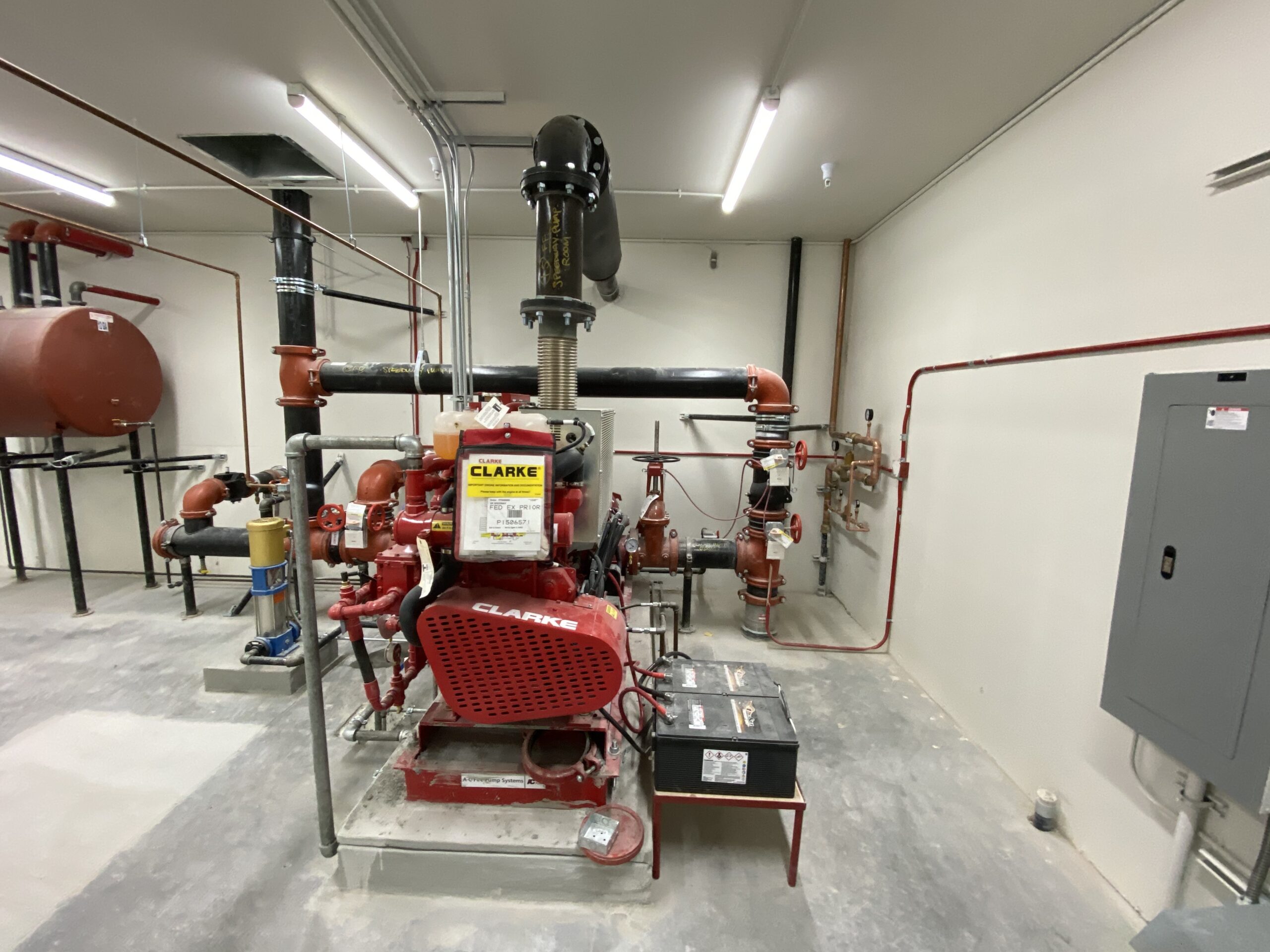 A pump-room full of red and black fire sprinkler pipes feeding into a central control unit. 